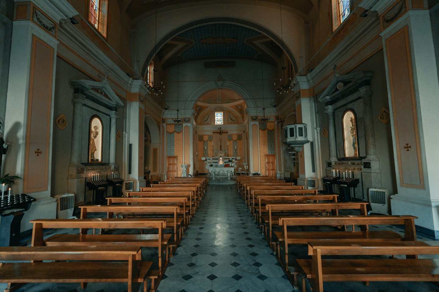 Puste drewniane ławki ustawione wzdłuż nawy prowadzącej do ozdobnego ołtarza.