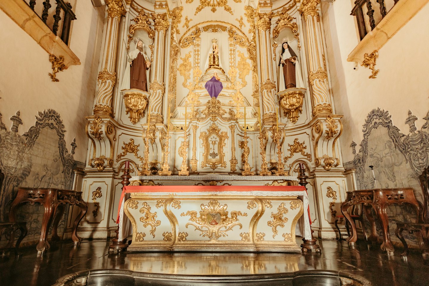 Ozdobny ołtarz kościelny ze złotymi rzeźbieniami i posągami świętych.